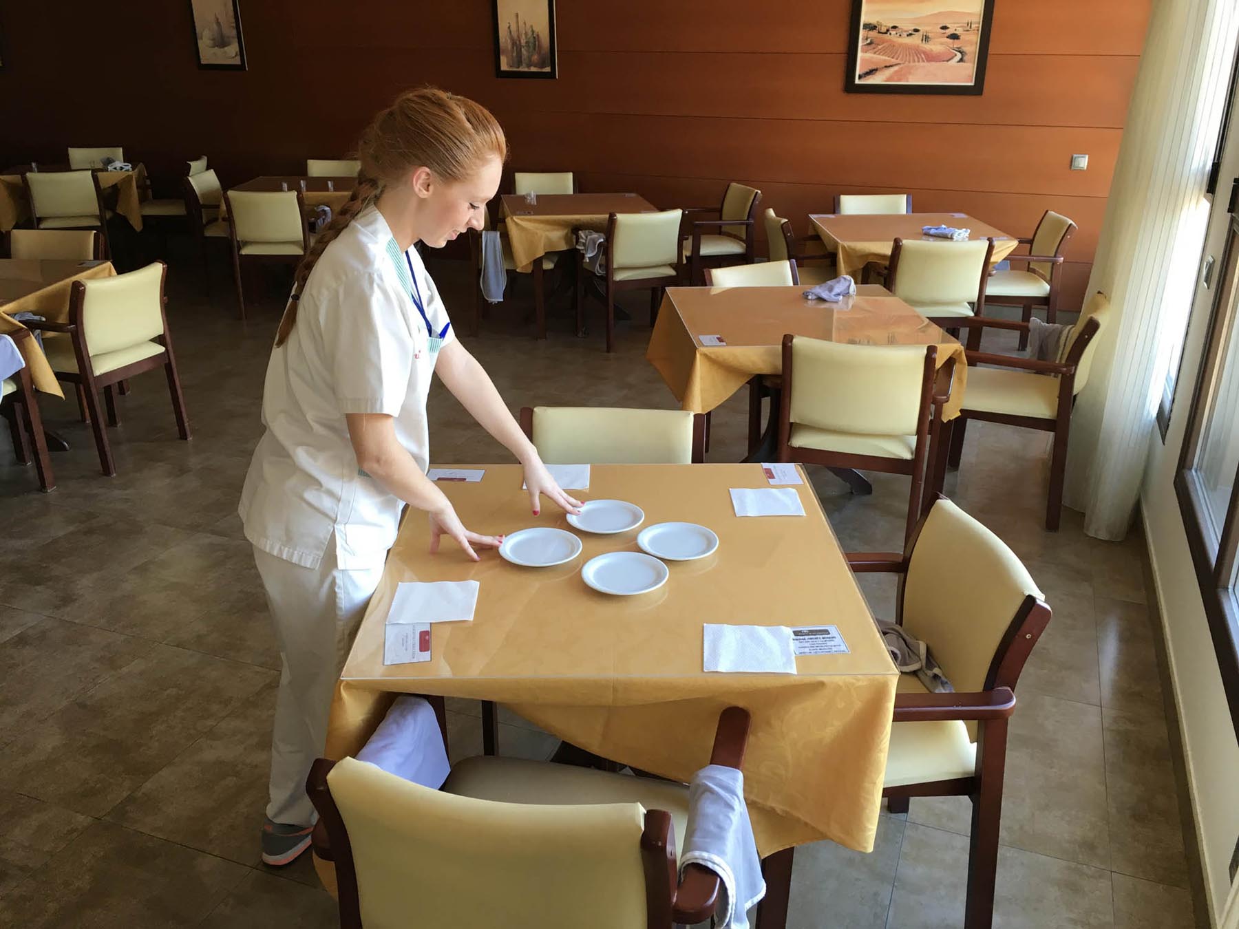 Trabajadora de la residencia poniendo las mesas del comedor
